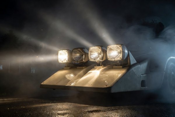Four Cibie halogen auxiliary lamps mounted in a fiberglass nose pod glowing in damp night fog
